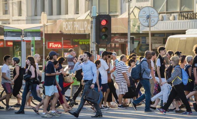 People walking across a crosswalk in downtown Melbourne.