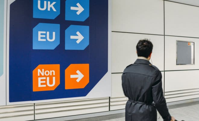 Passenger walks past sign pointing towards queues for UK, EU and Non-EU passport holders.