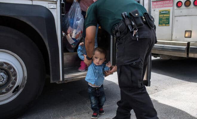 A 2-year-old boy from Honduras is helped off of a bus as he and his mother arrive at a bus station with other immigrants after being processed and released by U.S. Customs and Border Protection, in McAllen, Texas, June 24, 2018.