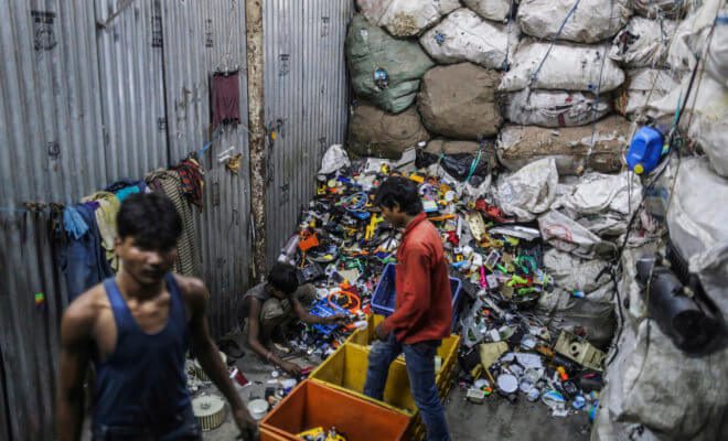Workers sort through plastic waste for recycling in the Dharavi slum area of Mumbai, India, on Aug. 11, 2014.