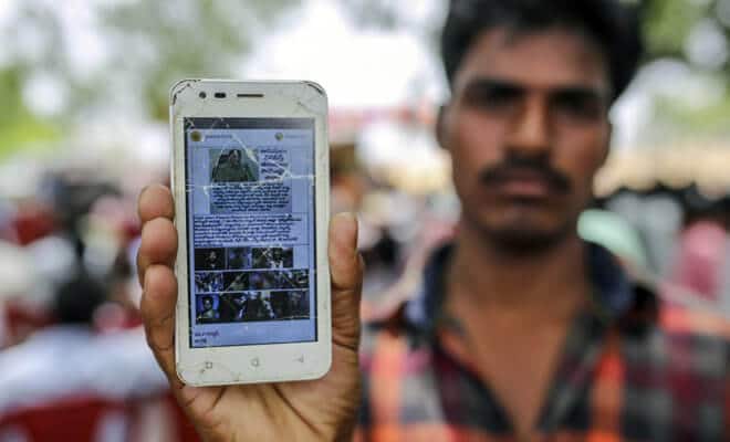 A man holds a mobile phone displaying a fake message shared on Facebook's WhatsApp messaging service while attending an event to raise awareness of fake news in Balgera village in the district of Gadwal, Telangana, India, on June 12.