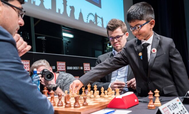 Shreyas Royal, 8, plays the ceremonial first move for Magnus Carlsen, center, against Vishy Anand at a chess tournament in London in 2017.