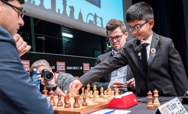 In a photo provided by his family, Shreyas Royal, 8, plays the ceremonial first move for Magnus Carlsen, center, against Vishy Anand at a chess tournament in London in 2017. (Family of Shreyas Royal via The New York Times)