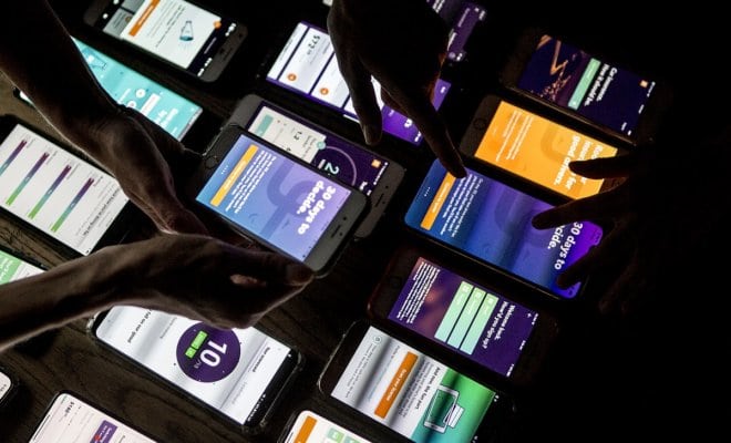 Employees at Root Insurance arrange smartphones displaying different screens of the company's app in Columbus, Ohio, on Oct. 3, 2018. The app uses smartphone sensors to pick up signals of risky driving behavior.