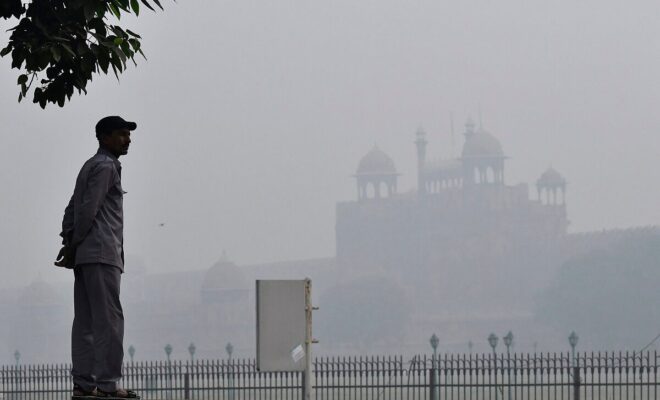 A man looks on in front of a building shrouded in smog in New Delhi on Nov. 11, 2017.